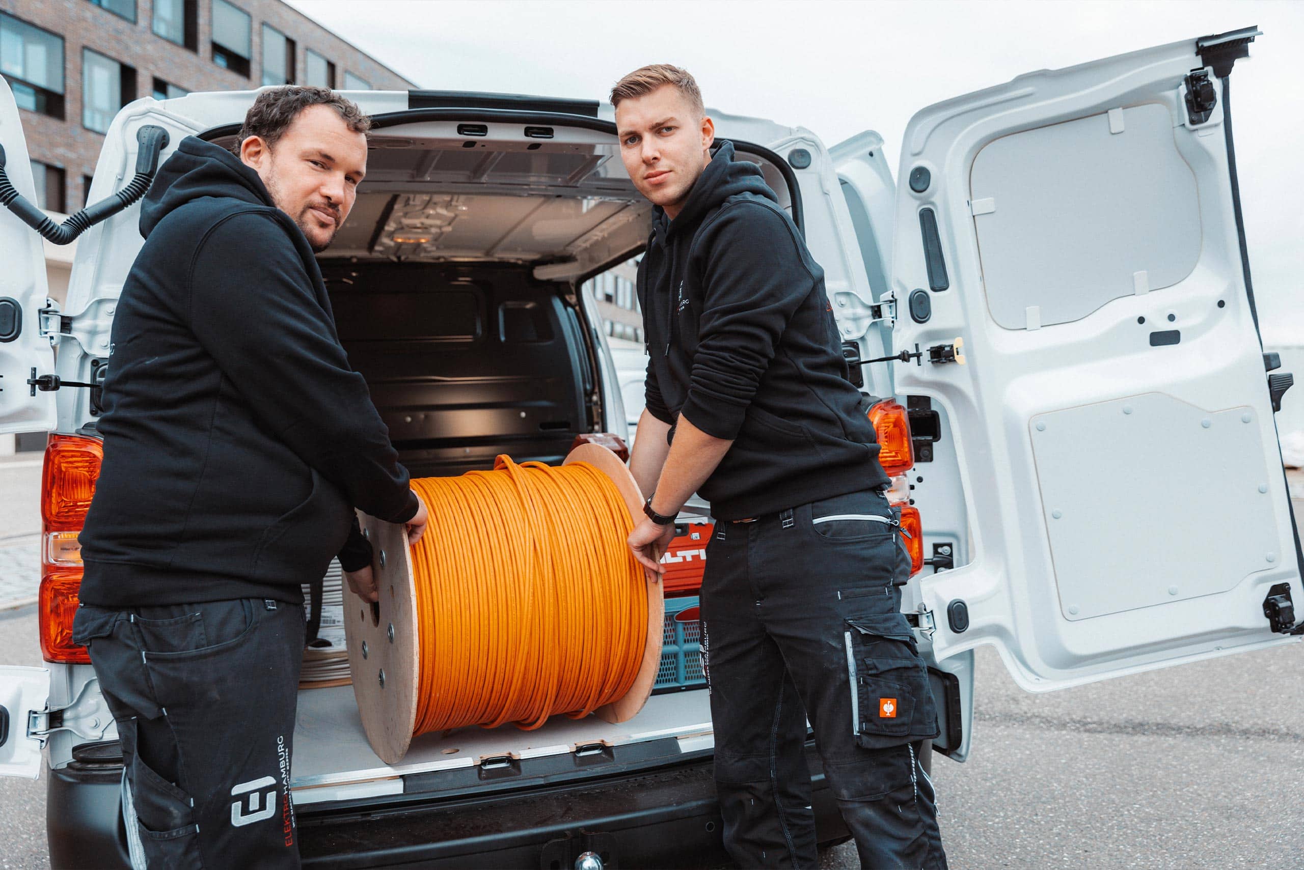 Zwei mitarbeiter elektrohamburg laden große kabeltrommel aus lieferwagen foto von ©jonas radtke